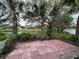 Scenic backyard with a red tile patio and lush landscaping with palm trees overlooking the water at 67 Marker Rd, Rotonda West, FL 33947