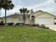Lovely home featuring an attached garage and manicured landscaping with a decorative palm tree at 67 Marker Rd, Rotonda West, FL 33947