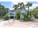 Charming three-story beach house with a light blue exterior, palm trees, and white railings at 7536 Palm Island S Dr # 1522, Placida, FL 33946