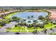 Aerial view of clubhouse with lake and parking surrounded by lush lawns and palm trees at 7620 Raptor Ct, North Port, FL 34287