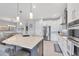 Bright kitchen featuring white cabinets, stainless steel appliances, a large island, and pendant lighting at 7620 Raptor Ct, North Port, FL 34287