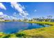 Panoramic view of the lake showcasing the lush green grass, residential houses and clear blue sky at 809 Tangerine Woods Blvd # 215, Englewood, FL 34223