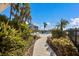 Landscaped backyard with a paved walkway leading to a pristine community pool at 11000 Placida Rd # 2702, Placida, FL 33946