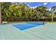 Up close view of the community tennis court showcasing blue and green coloring and a shaded tree line at 11000 Placida Rd # 2702, Placida, FL 33946