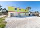 Bright two-story home with white rock landscaping, a sliding glass door, and tropical landscaping at 130 Sand Dollar Ln, Englewood, FL 34223