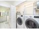 Washer and dryer located adjacent to the bathroom with white tile flooring at 130 Sand Dollar Ln, Englewood, FL 34223