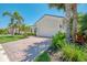 Beautifully landscaped home with lush green grass, palm trees, brick driveway and barrel tile roof at 13000 N Marsh Dr, Port Charlotte, FL 33953