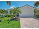 Beautifully landscaped home with lush green grass, palm trees, brick driveway and barrel tile roof at 13000 N Marsh Dr, Port Charlotte, FL 33953