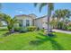 Beautifully landscaped home with lush green grass, palm trees, brick driveway and barrel tile roof at 13000 N Marsh Dr, Port Charlotte, FL 33953