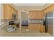 Open kitchen featuring granite countertops, mosaic backsplash, stainless steel appliances, and wooden cabinetry at 13217 Scrub Jay Ct, Port Charlotte, FL 33953