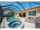 Sparkling pool and spa under a screened enclosure, with a covered patio for outdoor dining at 13217 Scrub Jay Ct, Port Charlotte, FL 33953