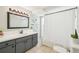 Bright bathroom featuring a gray vanity with white countertop, framed mirror, and shower with curtain at 1365 Sussex Rd, Venice, FL 34293