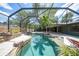 A backyard pool with a lounge chair, water features, and mature landscaping in a screened enclosure at 1386 Dewitt St, Port Charlotte, FL 33952