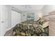 Bright bedroom features ceiling fan, wood-look floors, tropical-themed bedding and closet at 1401 S Mccall Rd # A 108, Englewood, FL 34223