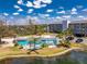 Aerial view of the community pool with a sun shelter, pond, and condo building in the background at 1401 S Mccall Rd # A 108, Englewood, FL 34223