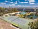 Aerial view of the community tennis court, pond, and pool alongside the condo buildings on a sunny day at 1401 S Mccall Rd # A 108, Englewood, FL 34223