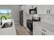 Modern kitchen with stainless steel appliances, white cabinets, and a view from the window at 166 Bunker Rd, Rotonda West, FL 33947