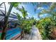 Lush tropical backyard with a brick path and swimming pool, creating a serene and inviting outdoor space at 1670 Faust Dr, Englewood, FL 34224
