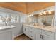 Bright bathroom featuring double sinks, white cabinetry, granite countertops and a wood plank ceiling at 17 Seawatch Dr, Boca Grande, FL 33921