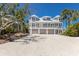 Elegant beach house with multiple garages, a large driveway, a balcony, and lush surrounding greenery at 17 Seawatch Dr, Boca Grande, FL 33921