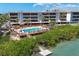 Scenic waterfront condo complex featuring a wooden pool deck, tiki hut, and mangrove views at 1701 Beach Rd # 208, Englewood, FL 34223