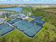 Aerial view showcases multiple tennis courts in a well-appointed community with lush landscaping at 17645 Boracay Ct # 202, Venice, FL 34293