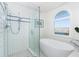 Bright bathroom featuring a soaking tub, tiled shower, and arched window at 180 S Gulf Blvd, Placida, FL 33946