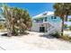Charming stilt home with white railing, stairs, and tropical landscaping at 180 S Gulf Blvd, Placida, FL 33946
