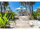 Exterior view of coastal beach home on stilts featuring beach sand landscaping and a metal roof at 180 S Gulf Blvd, Placida, FL 33946