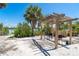 Lounge area beneath a pergola offers water views with two chairs, a table, and beach sand ground cover at 180 S Gulf Blvd, Placida, FL 33946