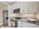 Galley kitchen featuring bright white cabinets, granite countertops, and stainless steel appliances at 20 Spaniards Rd, Placida, FL 33946