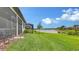 A well-maintained backyard features a lawn and a screened-in lanai facing a serene lake at 2117 Laurifolia Ct, North Port, FL 34289