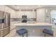 Modern kitchen features stainless appliances, tile backsplash, island with counter seating and pendant lighting at 2117 Laurifolia Ct, North Port, FL 34289