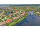 Aerial view of waterfront homes with mature landscaping, beautiful lake, and a red tile roof in gated community at 2669 Wax Myrtle Ct, Port Charlotte, FL 33953