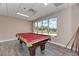 Well-lit game room with a full-size pool table and cues, plus a view from the expansive picture window at 2669 Wax Myrtle Ct, Port Charlotte, FL 33953