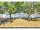 Backyard featuring well maintained green grass, mature trees, and a white privacy fence at 2821 Embassy Rd, North Port, FL 34291