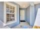 Covered entryway with a white front door, a window with blinds, and neutral-colored walls at 2821 Embassy Rd, North Port, FL 34291