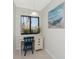 Cozy office nook with white desk, blue chair, natural light, and beach-themed artwork at 2955 N Beach Rd # D113, Englewood, FL 34223