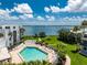 Resort-style pool overlooking the ocean, surrounded by lush landscaping and white lounge chairs under a blue sky with clouds at 2955 N Beach Rd # D113, Englewood, FL 34223