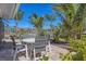 Outdoor patio area furnished with a round table and four chairs, surrounded by tropical plants and greenery at 30 Buccaneer Bnd, Placida, FL 33946