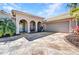 Beige home with arched entry and accent lighting sits adjacent to a two car garage at 3511 Bay Ridge Way, Port Charlotte, FL 33953