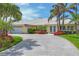 Inviting home with a well-maintained lawn and paver driveway, accented by tropical landscaping and large windows at 44 Waterford Dr, Englewood, FL 34223
