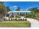 Beautifully landscaped front yard showcasing a modern home with light blue metal roof and circular drive at 4624 Pompano St, Placida, FL 33946
