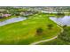 An aerial view of a lush golf course and ponds with a fountain, surrounded by luxurious houses and landscaping at 5433 White Ibis Dr, North Port, FL 34287