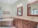 Bathroom featuring double vanity, soaking tub with tile surround, and natural light at 5433 White Ibis Dr, North Port, FL 34287