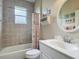 Well-lit bathroom features a tub with shower, a vanity, and decorative shelving at 5433 White Ibis Dr, North Port, FL 34287