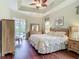 Inviting bedroom with backyard views, tray ceilings, wood floors, and ceiling fan at 5433 White Ibis Dr, North Port, FL 34287