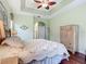 Cozy bedroom with tray ceiling, ceiling fan, wood floors, and arched doorway at 5433 White Ibis Dr, North Port, FL 34287