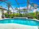 Screened-in pool with a water feature and lush tropical landscaping provides a relaxing outdoor oasis at 5433 White Ibis Dr, North Port, FL 34287