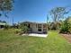 Cozy backyard featuring well-maintained grass, small patio area with seating, and the exterior of the house at 6181 Jack St, Venice, FL 34293